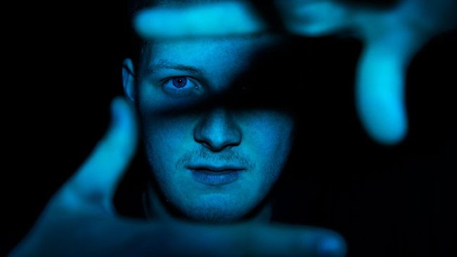 Mengenal Karakteristik dan Kemampuan 'Anak Indigo' Eye Contact Youth Portrait. Young teenage man showing picture frame with his hands towards the camera. Illuminated in blue light. Young People Teenage Lifestyle Portrait.