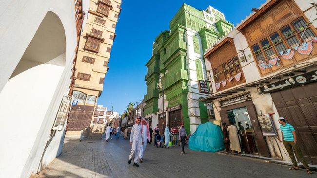 December 7th 2019, Jeddah, Saudi Arabia: The whole area (next to the green Noorwali House) was recently renovated and forms the main attraction of the old Jeddah nowadays. Many people (including two Saudi men in traditional clothes) are strolling along this street, as it leads into the Souk Baab Makkah, the traditional vegetable souk in Jeddah.
