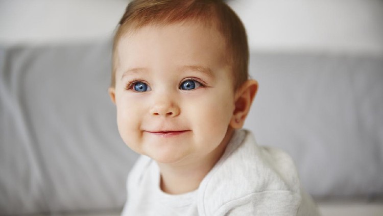 Close up of charming baby sitting on bed