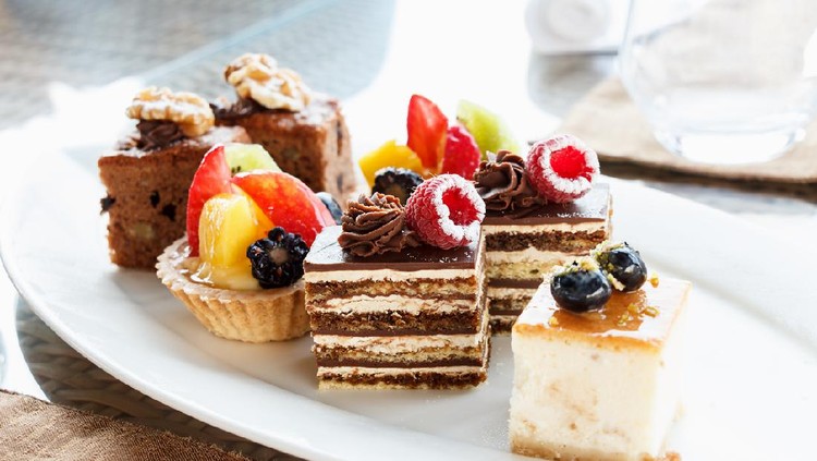 Set of mini cakes in assortment on white plate. Restaurant menu. Chocolate cake with raspberries. Tartlet with fruits.