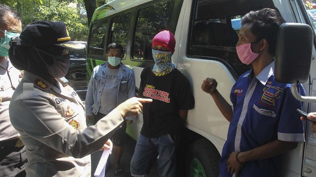 Polisi memeriksa sopir mikrobus yang mengangkut pemudik  di Surabaya, Jawa Timur, Rabu (13/5/2020). Pemudik dengan jasa travel yang melanggar larangan mudik itu didata dan selanjutnya dipulangkan ke tempat asal sedangkan tujuh kendaraan mikrobus dari jasa travelnya dilakukan penindakan tilang. ANTARA FOTO/Didik Suhartono/foc.