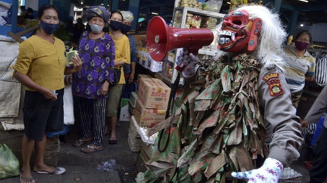 Petugas kepolisian yang mengenakan kostum menyeramkan 'Celuluk' melakukan sosialisasi langkah-langkah pencegahan COVID-19 di Pasar Tradisional Sempidi, Badung, Bali, Selasa (12/5/2020). Kegiatan yang dilakukan petugas kepolisian Polres Badung di sejumlah pasar tradisional dan ruas jalan tersebut dilakukan untuk mengimbau masyarakat terus melakukan berbagai upaya pencegahan penyebaran COVID-19 seperti mengenakan masker, rutin mencuci tangan, menjaga jarak serta tidak melakukan perjalanan mudik. ANTARA FOTO/Fikri Yusuf/foc.