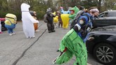 Parade Kostum Hiburan Ditengah Pandemi Corona In this Monday, May 11, 2020 photo, Keely Crimando, a member of the T-Rex Walking Club, puts on her costume in Ferndale, Mich. The group takes its unannounced strolls through neighborhoods on a quest to bring smiles to the faces of kids, and a few adults, while under Michigan's stay-at-home order because of the COVID-19 pandemic. (AP Photo/Carlos Osorio)