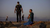 nyalang Edisi 16 Mei 2020 A police officer talks to a man meditating in a beach reopened for sport activities after the lockdown measures imposed by the government in Barcelona, Spain, Friday, May 8, 2020. In last minute negotiations, Spain's government has secured enough parliamentary support to extend later on Wednesday the country's state of emergency. Spain has recorded over 25,600 deaths from the new coronavirus. (AP Photo/Emilio Morenatti)