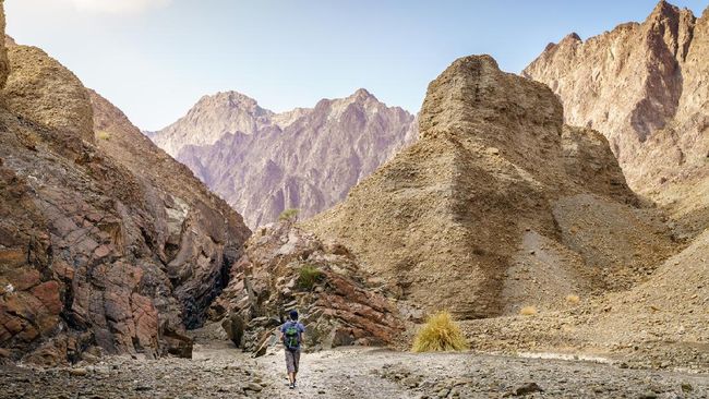 A man is hiking through a wadi in Hajar Mountains near Hatta, UAE