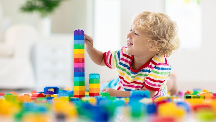 1137822098 Child playing with colorful toy blocks. Little boy building tower at home or day care. Educational toys for young children. Construction block for baby or toddler kid. Mess in kindergarten play room.