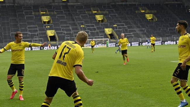 Dortmund's Erling Haaland, back to camera, celebrates after scoring the opening goal during the German Bundesliga soccer match between Borussia Dortmund and Schalke 04 in Dortmund, Germany, Saturday, May 16, 2020. The German Bundesliga becomes the world's first major soccer league to resume after a two-month suspension because of the coronavirus pandemic. (AP Photo/Martin Meissner, Pool)