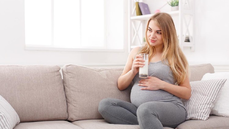 Pregnant woman drinking glass of milk copy space. Young expectant blonde enjoying healthy drink. Healthcare, nutrition, vitamins, pregnancy concept