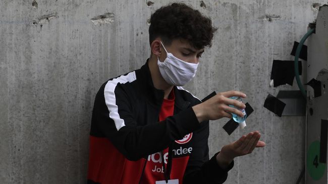 A ball boy uses a hand sanitizer prior the German Bundesliga soccer match between Eintracht Frankfurt and Borussia Moenchengladbach in Frankfurt, Germany, Saturday, March 16, 2020. The German Bundesliga becomes the world's first major soccer league to resume after a two-month suspension because of the coronavirus pandemic. (AP Photo/Michael Probst, Pool)