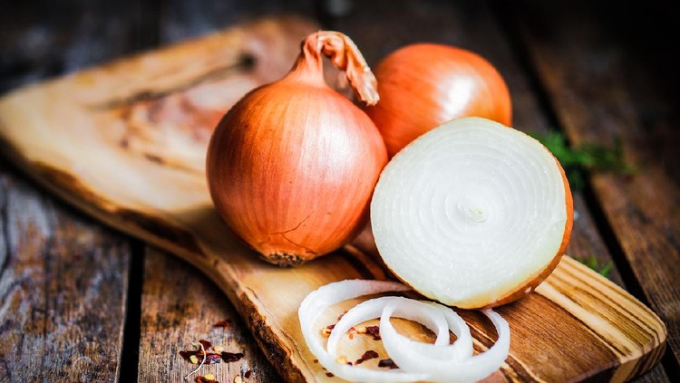 Golden onions on rustic wooden background