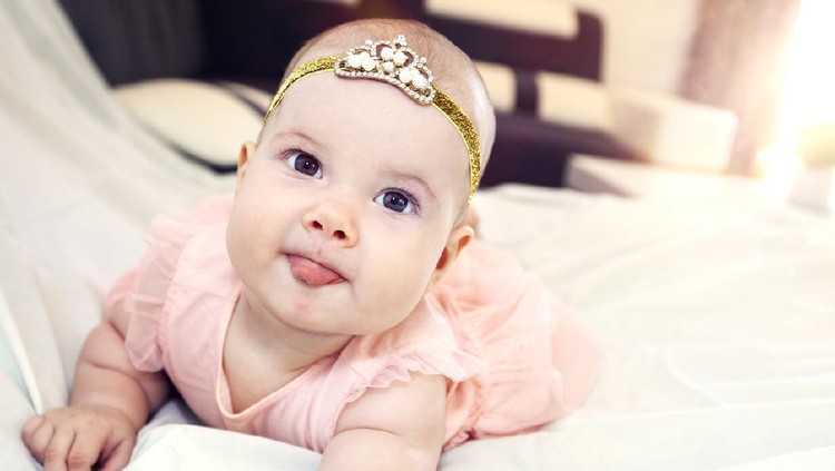 Happy baby girl. The little girl stretches out her tongue