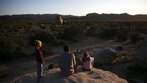 Wisata Taman Nasional Joshua Tree di California Aaron Stubbs and his two children sit on a rock to watch sunset at Joshua Tree National Park in California, Tuesday, May 19, 2020. The park reopened this week after a lengthy closure to help slow the spread of the new coronavirus. (AP Photo/Jae C. Hong)