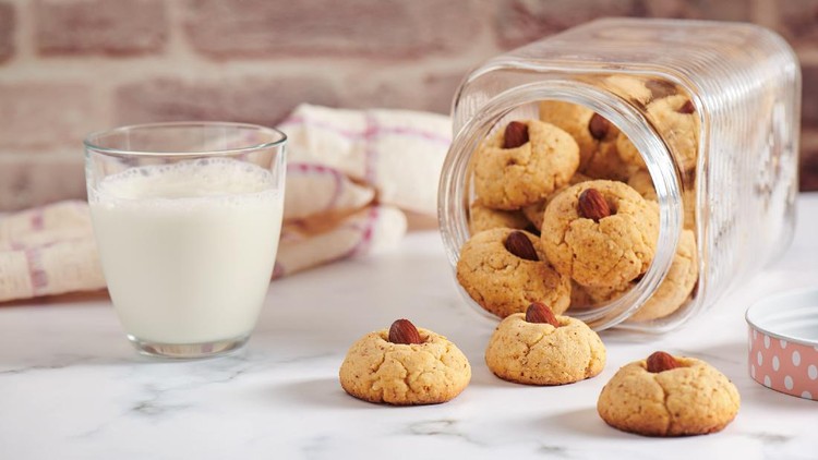 Turned jar with dropped out almond cookies, glass of milk