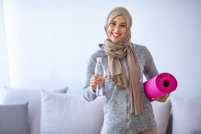 Muslim woman preparing for workout. Young muslim woman ready to running. Islamic woman resting and drinking water. Portrait of muslim woman likes her active life.