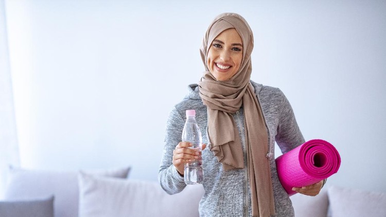 Muslim woman preparing for workout. Young muslim woman ready to running. Islamic woman resting and drinking water. Portrait of muslim woman likes her active life.