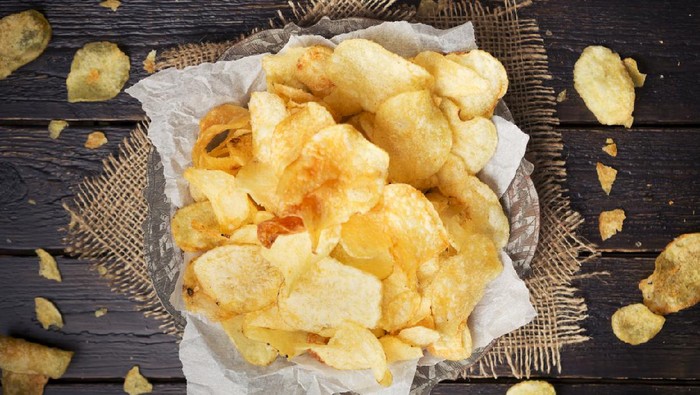A bowl of potato chips on a rustic table.