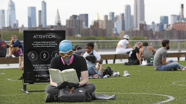 Social Distancing Saat Berjemur di Taman Ala Warga New York Ridley Goodside wears a goggles and a filtration mask to protect himself from exposure to coronavirus as he reads