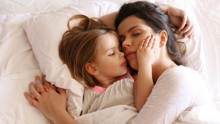 Mother with her daughter  slipping in bed.