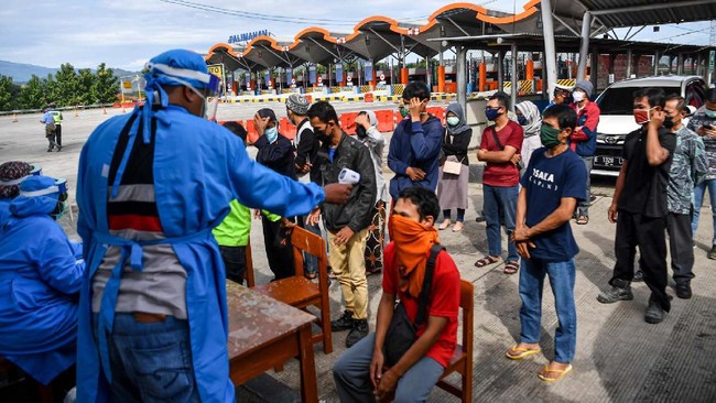 Petugas kesehatan memeriksa suhu tubuh pemudik yang melintas di pintu Tol Cipali Palimanan, Cirebon, Jawa Barat, Kamis (21/5/2020). Pemeriksaan tersebut sebagai upaya penyekatan gelombang pemudik jelang perayaan Hari Raya Idul Fitri 1441 H dari arah Jakarta menuju Jawa Tengah. ANTARA FOTO/Nova Wahyudi/nz