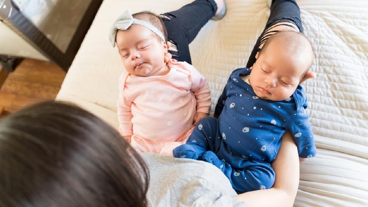 1157671472 High angle view of mother holding adorable twin kids on bed
