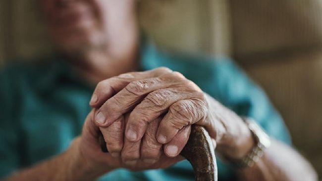 Cropped shot of an unrecognizable man leaning on his walking stick