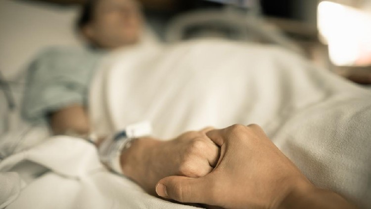 Man holding hand, giving support and comfort to woman, loved one sick in hospital bed.