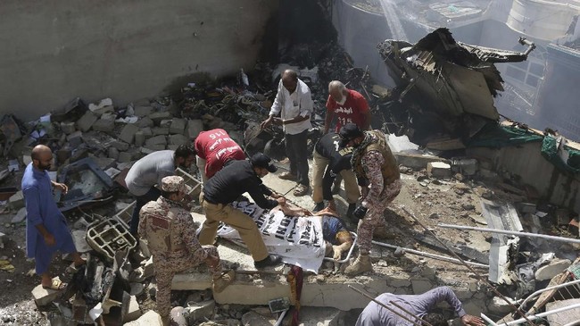 Volunteers cover the dead body of a plane crash victim at the site of the crash in Karachi, Pakistan, Friday, May 22, 2020. An aviation official says a passenger plane belonging to state-run Pakistan International Airlines carrying more than 100 passengers and crew has crashed near the southern port city of Karachi. There were no immediate reports on the number of casualties. (AP Photo/Fareed Khan)