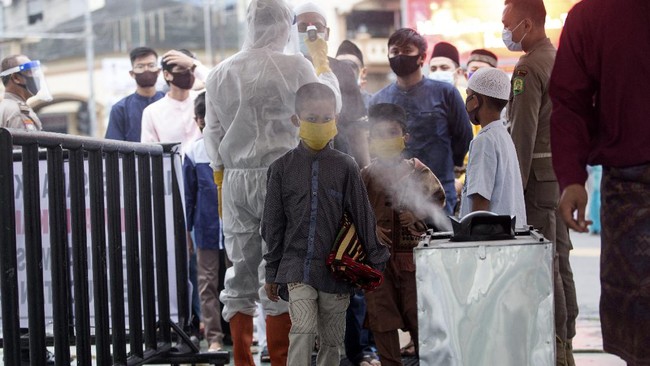 A boy walks past a disinfectant sprayer at the Al Mashun Grand Mosque to attend Eid al Fitr prayer amid concerns of coronavirus outbreak in Medan, North Sumatra, Indonesia, Sunday, May 24, 2020. Millions of people in the world's largest Muslim nation are marking a muted and gloomy religious festival of Eid al-Fitr, the end of the fasting month of Ramadan _ a usually joyous three-day celebration that has been significantly toned down as coronavirus cases soar. (AP Photo/Binsar Bakkara)