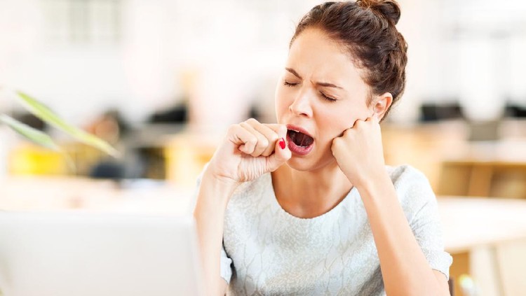Tired female entrepreneur yawning in office. Horizontal shot.