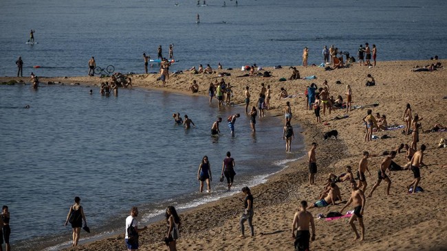People enjoy the beach in Barcelona, Spain, Wednesday, May 20, 2020. Barcelona allowed people to walk on its beaches Wednesday, for the first time since the start of the coronavirus lockdown over two months ago. Sunbathing and recreational swimming are still not allowed. (AP Photo/Emilio Morenatti)