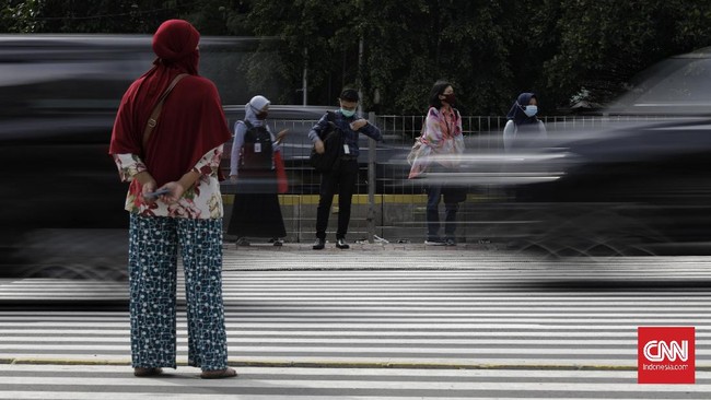 Sejumlah pekerja berjalan dengan latar belakang gedung perkantoran, Jakarta, Kamis (16/4/2020). H+2 lebaran jalan Jakarta terpantau ramai selama masa Pembatasan Sosial Berskala Besar (PSBB) tahap tiga di Jakarta. (CNN Indonesia/ Adhi Wicaksono)