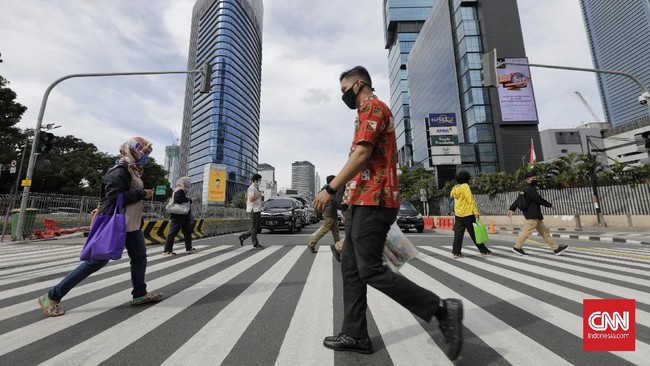 Sejumlah pekerja berjalan dengan latar belakang gedung perkantoran, Jakarta, Kamis (16/4/2020). H+2 lebaran jalan Jakarta terpantau ramai selama masa Pembatasan Sosial Berskala Besar (PSBB) tahap tiga di Jakarta. (CNN Indonesia/ Adhi Wicaksono)