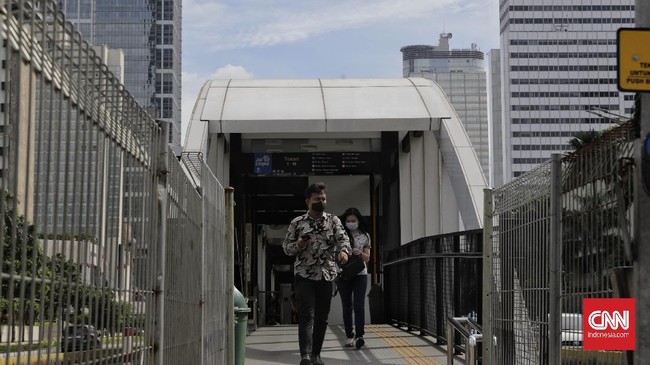Sejumlah pekerja berjalan dengan latar belakang gedung perkantoran, Jakarta, Kamis (16/4/2020). H+2 lebaran jalan Jakarta terpantau ramai selama masa Pembatasan Sosial Berskala Besar (PSBB) tahap tiga di Jakarta. (CNN Indonesia/ Adhi Wicaksono)