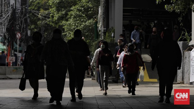 Sejumlah pekerja berjalan dengan latar belakang gedung perkantoran, Jakarta, Kamis (16/4/2020). H+2 lebaran jalan Jakarta terpantau ramai selama masa Pembatasan Sosial Berskala Besar (PSBB) tahap tiga di Jakarta. (CNN Indonesia/ Adhi Wicaksono)