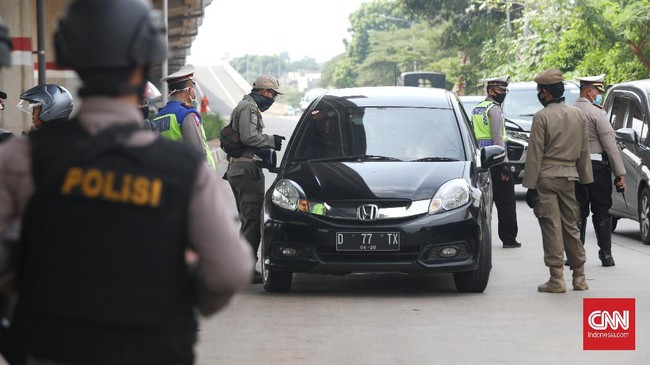 Petugas gabungan (TNI, Polisi, Satpol PP) melakukan pengecekan surat izin keluar masuk (SIKM)  Jakarta bagi pengendara motor dan mobil di check point Lampiri, Jakarta Timur, Rabu, 27 Mei 2020. Bagi pengendara mobil maupun motor yang ber-plat diluar Jabodetabek dan tak dapat menunjukkan SIKM diwajibkan memutar balik kendaraan. CNNIndonesia/Safir Makki