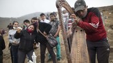 Peru Jadi Hotspot Penyebaran COVID-19 Harpist and cemetery worker Charlie Juarez performs while Gregoria Zumaeta, 44, left, mourns the death of her brothers Jorge Zumaeta, 50, and Miguel Zumaeta, 54, who died from COVID-19, at the Nueva Esperanza cemetery on the outskirts of Lima, Peru, Tuesday, May 26, 2020. (AP Photo/Rodrigo Abd)