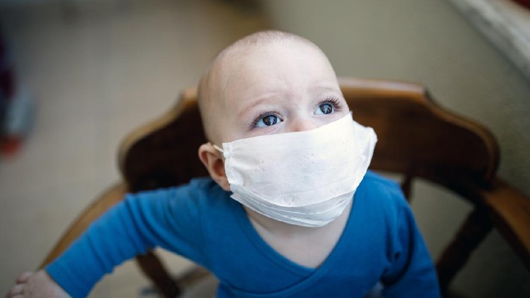 A little boy puts a medical mask on his face.