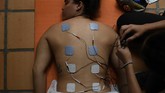 Impian Berlaga di Olimpiade Bagi Atlet BMX Venezuela yang Terkurung Venezuelan Olympic medalist Stefany Hernandez, a BMX racing cyclist, receives electro-stimulation pads on her back during a muscle relaxation session with her physical therapist at her home in Caracas, Venezuela, Monday, May 25, 2020. Despite a quarantine to curb the spread of COVID-19, Hernandez trains three times a week in hopes of qualifying for the 2021 Tokyo Summer Olympics. (AP Photo/Matias Delacroix)