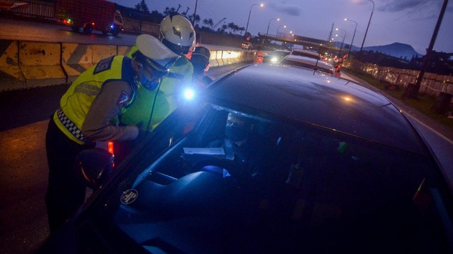 Petugas kepolisian memeriksa kelengkapan pengemudi saat penyekatan arus balik menuju Jakarta di Gerbang masuk Tol Cileunyi, Kabupaten Bandung, Jawa Barat, Rabu (27/5/2020). Pada penyekatan arus balik tersebut petugas memeriksa surat tugas kantor dan surat izin keluar masuk (SIKM) pada pengemudi yang berkendara dengan menggunakan Plat B serta meminta pengendara memutar balik jika tidak memiliki SIKM. ANTARA FOTO/Raisan Al Farisi/foc.