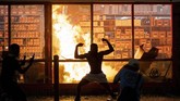 Kerusuhan di Minneapolis A man poses for photos in front of a fire at an AutoZone store, while protesters hold a rally for George Floyd in Minneapolis on Wednesday, May 27, 2020. Violent protests over the death of the black man in police custody broke out in Minneapolis for a second straight night Wednesday, with protesters in a standoff with officers outside a police precinct and looting of nearby stores. (Carlos Gonzalez/Star Tribune via AP)