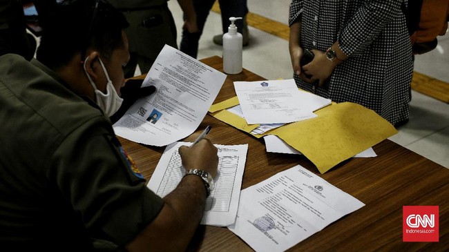 Penumpang KLB Lintas Selatan dari Pasar Turi Surabaya tiba di Stasiun Gambir, Jakarta, Kamis (28/05/2020). Penumpang yang tiba langsung disambut oleh petugas gabungan untuk diperiksa kelengkapan Surat Izin Keluar Masuk (SIKM) dari daerah ke Jakarta, Surat Keterangan Kerja, Surat Keterangan Kesehatan dan Identitas Diri. Apabila tidak melengkapi persyaratan tersebut penumpang telah disediakan bus untuk di antarkan ke lokasi Karantina yang telah disediakan sebagai bagian dari penyekatan keluar masuknya warga dengan tujuan memutus mata rantai penyebaran covid-19. CNN Indonesia/Andry Novelino