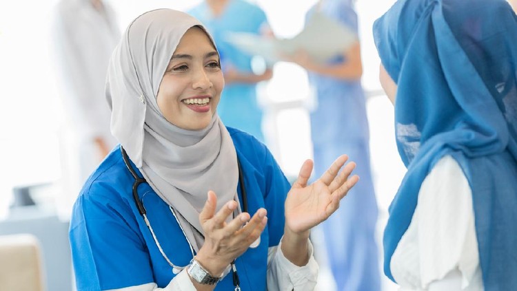Cheerful female nurse gestures as she talks with a pregnant patient.