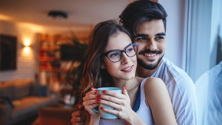1148807699 Portrait of a happy young couple cuddling at home.