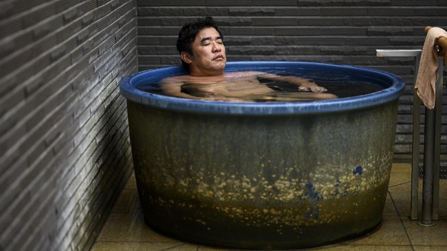 In this picture taken on May 29, 2020, Masazumi Kato relaxes in a tub at a Japanese hot spring or onsen in Yokohama, Kanagawa prefecture. - With the lifting of a nationwide state of emergency over the virus, Japan's onsen -- large bathhouses where patrons bathe naked in a series of warm pools and tubs -- are gradually reopening. (Photo by Behrouz MEHRI / AFP) / TO GO WITH AFP STORY 'JAPAN-VIRUS-HEALTH-LIFESTYLE-BATH' FOCUS BY HIROSHI HIYAMA