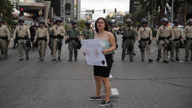 A woman protesting the death of George Floyd stands in front of a line of police along Las Vegas Boulevard, Friday, May 29, 2020, in Las Vegas. Floyd died on Memorial Day while in the custody of the Minneapolis police. (AP Photo/John Locher)