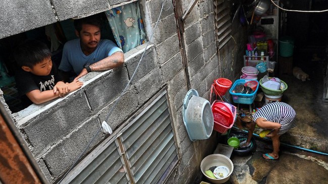 This photo taken on May 30, 2020 shows motorcycle taxi driver, Thanapat Noidee with son Kittipat looking from the window of their home in Bangkok. - Shuffling around their tiny slum home which is too small to stand up in, a couple share donated noodles with their sons and worry about how they will pay the bills, as the coronavirus pushes Thailand's poor deeper into penury. (Photo by Romeo GACAD / AFP) / TO GO WITH Health-virus-Thailand-economy-poverty by Pitcha DANGPRASITH