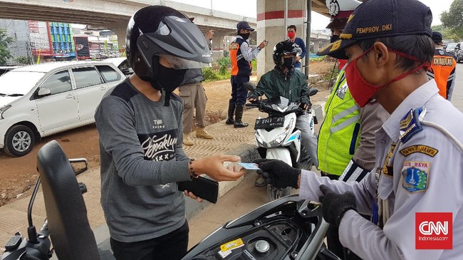 Petugas gabungan dari Dinas Perhubungan, Satpol PP, hingga kepolisian memeriksa kelengkapan administrasi bagi warga yang hendak melintas ke wilayah DKI Jakarta, Minggu (31/5). Bagi warga yang tidak ber-KTP Jabodetabek dan tidak membawa surat izin keluar masuk (SIKM) Jakarta akan diputar balik.