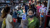 Aktivitas New Normal di Thailand A police officer measures body temperatures of visitors entering a market area in Bangkok, Thailand, Tuesday, May 12, 2020. People with body temperature exceeding 37.5 degree Celsius, (99.5 Fahrenheit) or potential symptoms of COVID-19 are typically barred from entering communal areas. (AP Photo/Gemunu Amarasinghe)