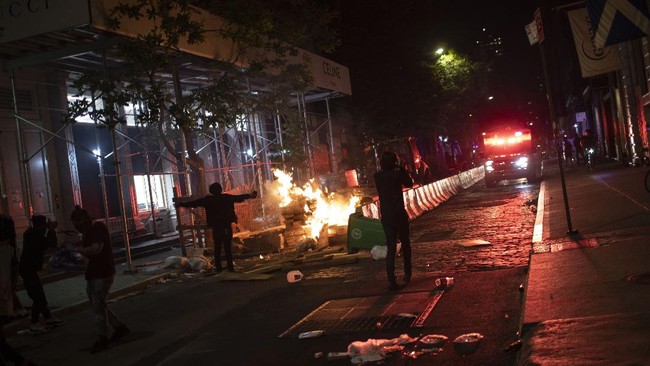 Protesters run down a street where a fire was started outside a Gucci store during a rally for George Floyd, Sunday, May 31, 2020, in New York. Protests were held throughout the city over the death of Floyd, a black man in police custody in Minneapolis who died after being restrained by police officers on Memorial Day. (AP Photo/Wong Maye-E)