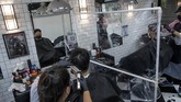 Aktivitas New Normal di Thailand Barbers divided by a plastic partitions cut hair in a small shop in Bangkok, Thailand, Saturday, May 23, 2020. The Thai government continues to ease restrictions on businesses and services in Bangkok that were imposed weeks ago to combat the spread of the coronavirus. (AP Photo/Gemunu Amarasinghe)